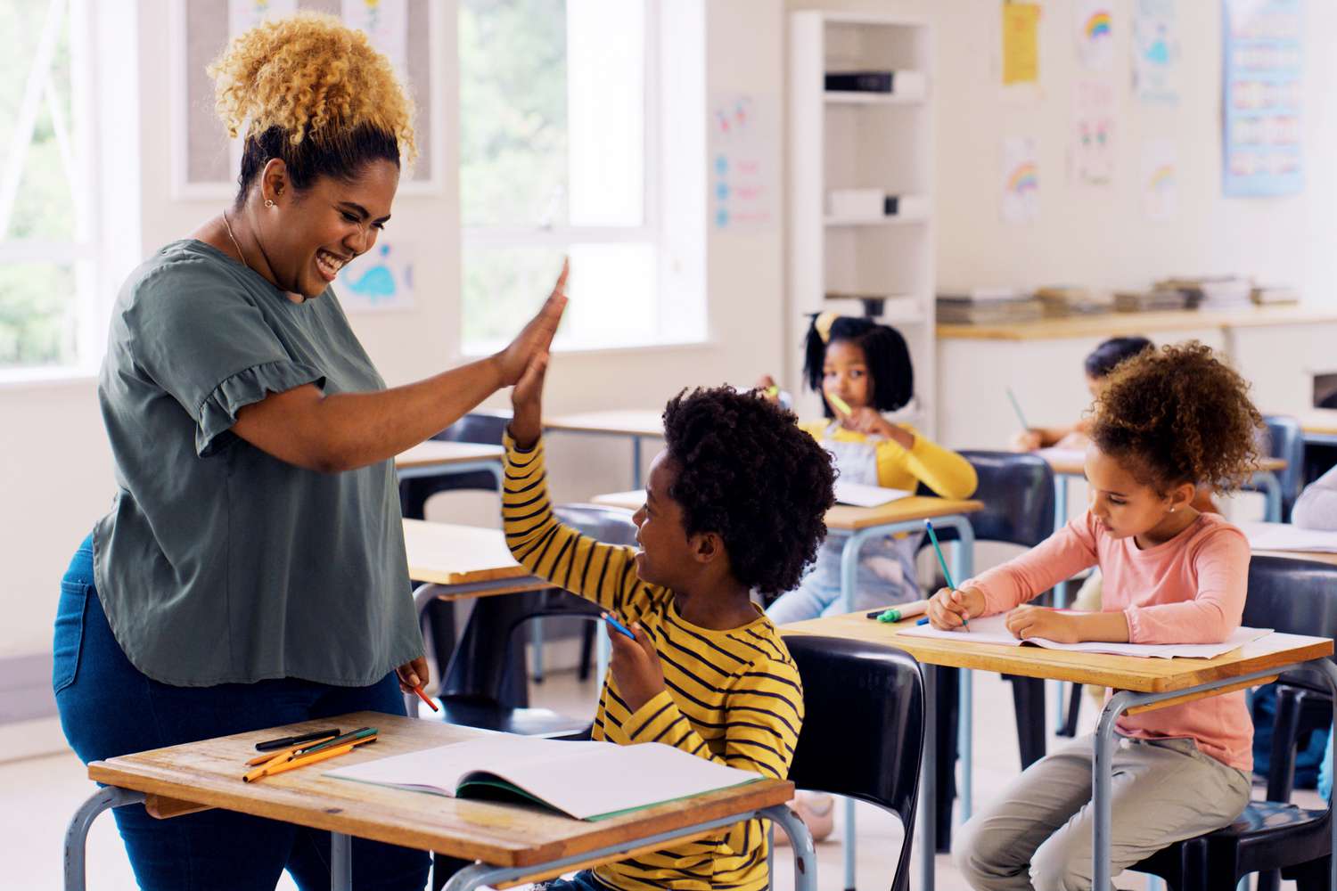 A teacher and student sharing a high-five in a classroom