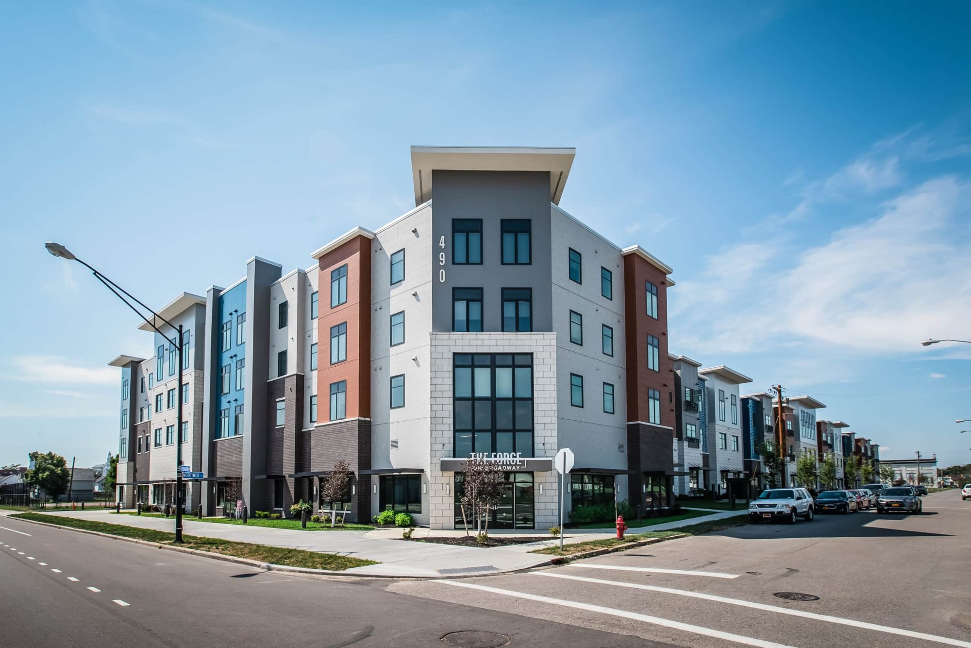 The Forge on Broadway — modern four-story mixed-use apartment building with multicolor façade panels on a Buffalo street corner